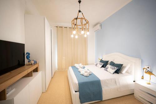 a white bedroom with a bed and a chandelier at Deledda Rooms Boutique in Budoni