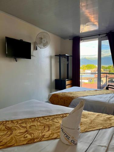 a hotel room with two beds and a window at Hotel Olam Confort in Villavicencio
