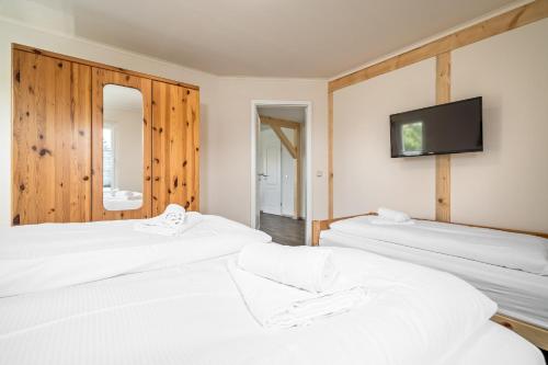three white beds in a room with a flat screen tv at Ferienhaus Alt-Gaarz in Lärz