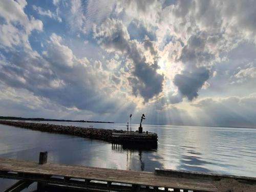 a pier in the water under a cloudy sky at Bogense Ferieboliger 500 m til kysten in Bogense