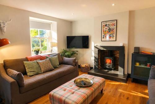 a living room with a couch and a fireplace at Bakers Yard Cottage, Bonsall, Peak District in Bonsall