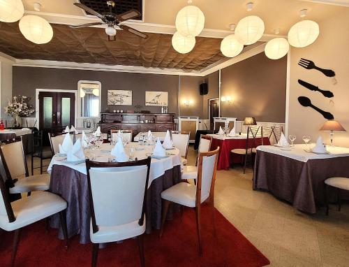 a dining room with white tables and chairs at Logis Hôtel Le Merle Blanc in Digoin