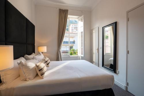 ein Schlafzimmer mit einem großen weißen Bett und einem Fenster in der Unterkunft Hotel De Monaco in Cap d'Ail