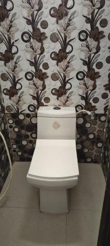 a toilet in a bathroom with a floral wallpaper at Hotel Ansh Palace - Village Near Taj Mahal Agra in Tājganj