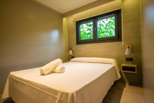 a bedroom with two beds with white sheets and a window at Camping Port Massaluca in Pobla de Masaluca