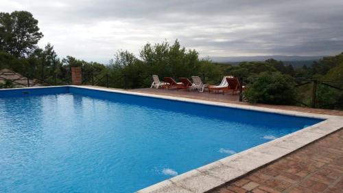 una gran piscina azul con algunas sillas en Cabañas El Tirol en La Falda