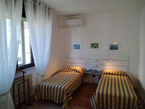 a bedroom with two beds and a desk and a window at Alle Nuove Stelle in Udine