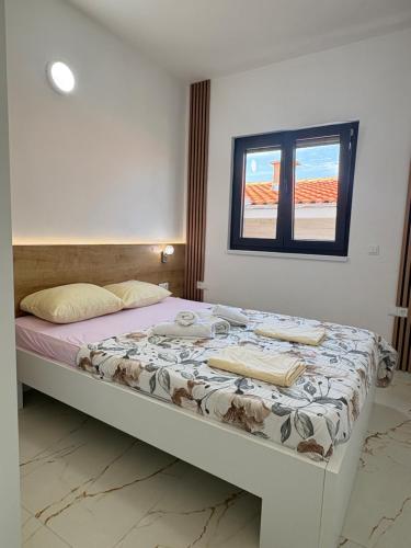 a bed in a room with a window at Apartmani Catakovic in Vir