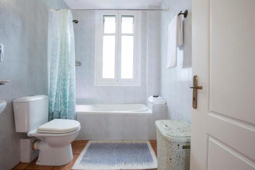 a bathroom with a toilet and a tub and a window at Palairos Historic Villa in Paleros
