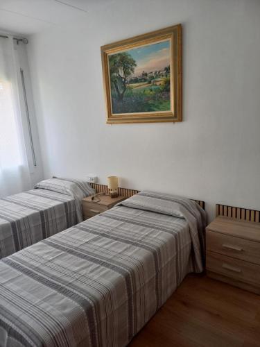 two beds in a room with a picture on the wall at Apartament Can Jaumató in Sant Quirze de Besora