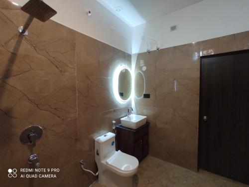 a bathroom with a toilet and a sink and a mirror at Glotus Hotel in Herbertpur