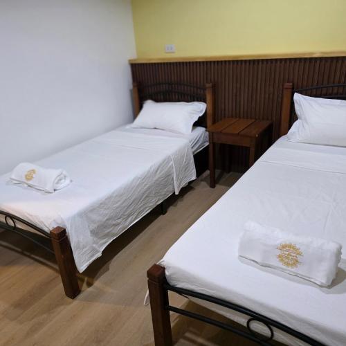 two beds in a room with white sheets at Sunflower Residences Capitol formerly mayflower inn in Cebu City
