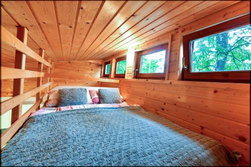 a bed in a log cabin with two windows at Tiny House Grabovac in Rakovica