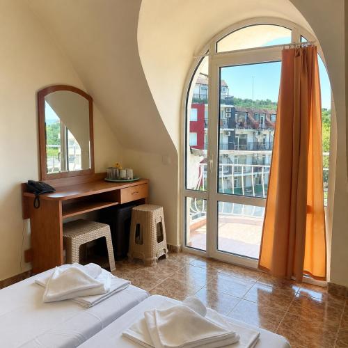 a bedroom with a desk and a bed and a window at Hotel Palace in Kranevo