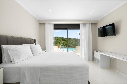 a white bedroom with a large bed and a window at Meganisi Villas Royal in Meganisi