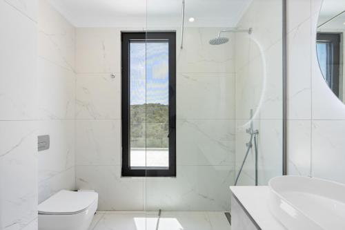 a white bathroom with a toilet and a sink at Meganisi Villas Royal in Meganisi