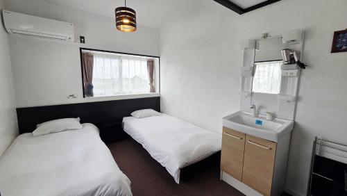 ein Zimmer mit zwei Betten, einem Waschbecken und einem Spiegel in der Unterkunft Atria CHIKURA in Minamiboso