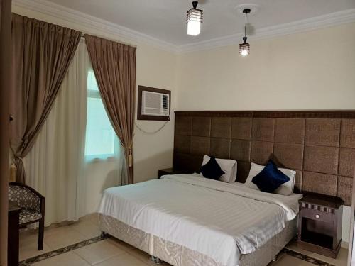 a bedroom with a large bed with blue pillows at الامتياز in Jeddah