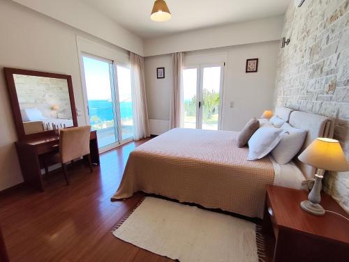 a bedroom with a bed and a desk and windows at Villa Tholos Crete in Kavoúsion