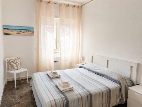 a white bedroom with a bed and a chair at Casa Atena in Sperlonga
