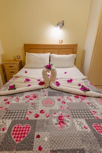 a bed with pink flowers and hearts on it at MARINA in Perama