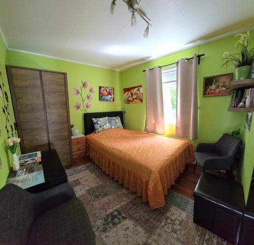 a bedroom with green walls and a bed and a chair at Gjesterom til leie i et privat hus 250 moh in Brumunddalen