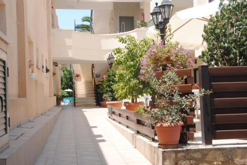 an alley in a building with flowers in pots at C & A Hotel Apartments in Polis Chrysochous
