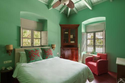 a green bedroom with a bed and a red chair at Cactus Hydra - Art Apartments in Hydra