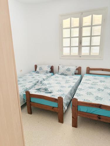 two twin beds in a room with a window at Appartement de plage d in As Suwaysah