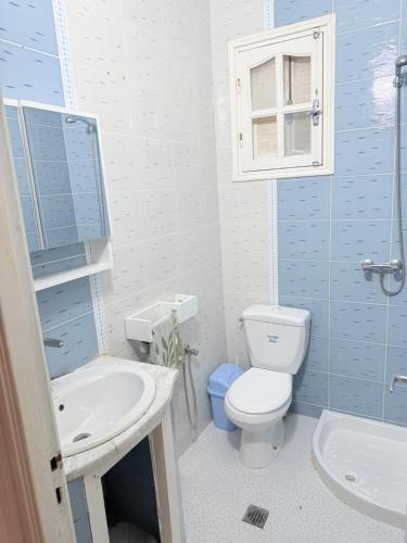 a blue and white bathroom with a toilet and a sink at Appartement de plage d in As Suwaysah