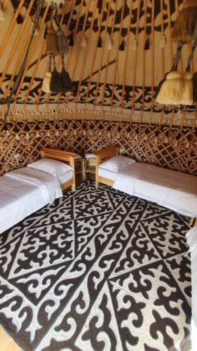 a room with two beds and a black and white rug at Elizabet guest house in Kerben