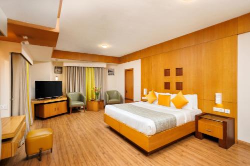 a hotel room with a bed and a flat screen tv at Meadows Residency in Ooty