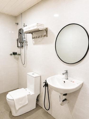 a bathroom with a sink and a mirror and a toilet at SS Hotel Seremban in Seremban