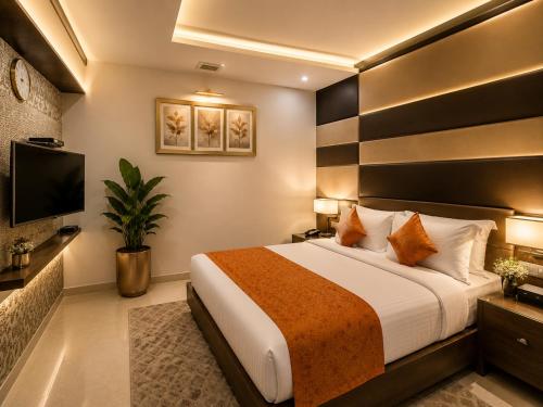 a hotel room with a bed and a flat screen tv at Hotel Indraprasttha in Vijayawāda