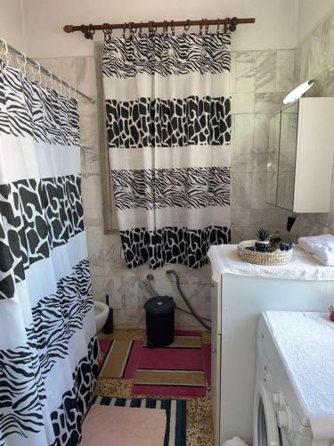 a bathroom with black and white shower curtains and a washing machine at John's House in Chalkida