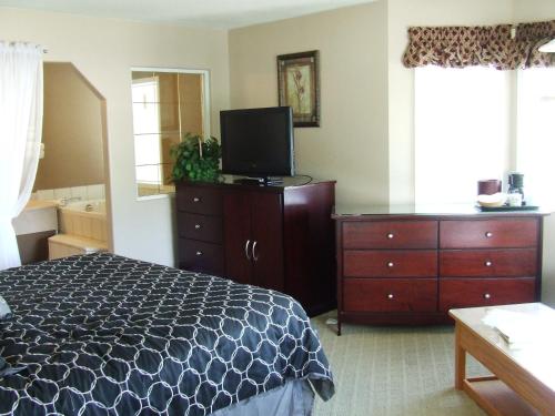 a bedroom with a bed and a dresser and a television at Ponderosa Motor Inn in Golden