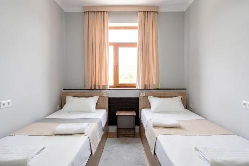 two beds in a small room with a window at BESQALA in Nukus