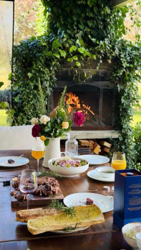 a table with food and glasses of wine and a fireplace at The Black Barn At Puketitiri in Puketitiri