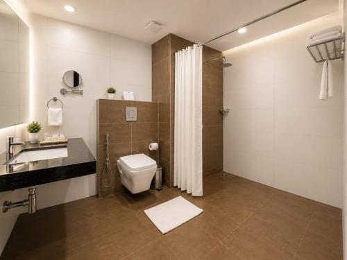 a bathroom with a toilet and a sink and a shower at Hotel Indraprasttha in Vijayawāda