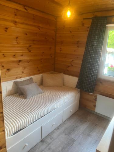 a bed in a wooden cabin with a window at Rajski Domek Rajsko in Bożkowice