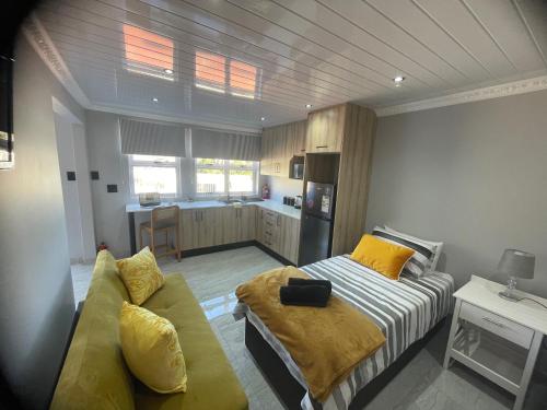 a room with a bed and a couch and a kitchen at Abijah Ridgeview Studios in Roodepoort