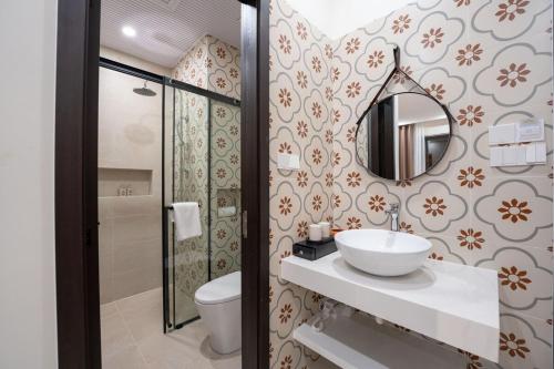 a bathroom with a sink and a toilet and a mirror at Maison De Hoi An Boutique Homestay in Hoi An