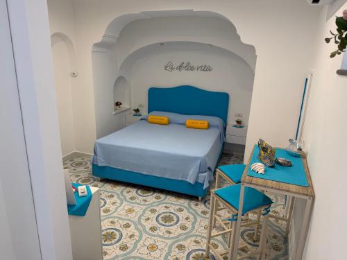 a bedroom with a blue bed and a table at La Piccola Suite in Anacapri