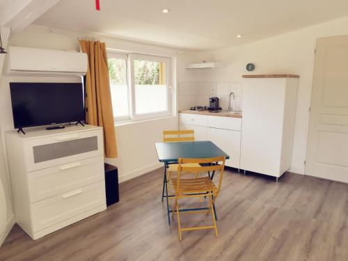 a kitchen and dining room with a table and a television at Omnia in Saint-Maixent-lʼÉcole
