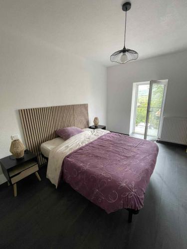 a bedroom with a large bed with a purple blanket at Appartement à Vouglans in Lect