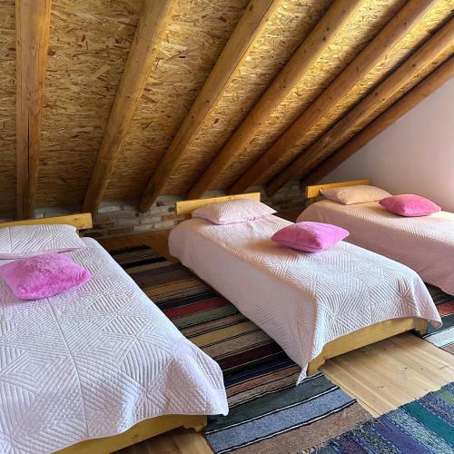 two beds in a attic room with pink pillows at Vila Ramaj in Berat