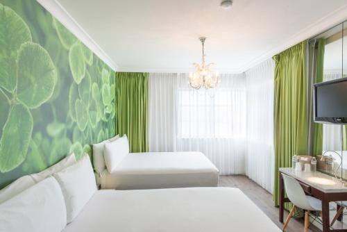 a bedroom with two white beds and a green wall at President Hotel in Miami Beach