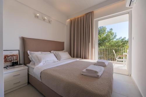 a bedroom with a bed and a large window at PJ Properties Riviera Escape Suite Sounio in Sounio