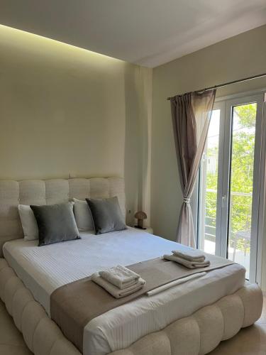 a white bedroom with a large bed with a window at Amare casa in Perivólia