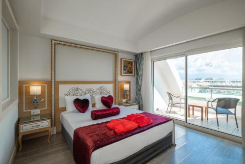 a bedroom with a bed with red pillows and a balcony at Crystal Waterworld Aqua Collection - Ultimate All Inclusive in Belek
